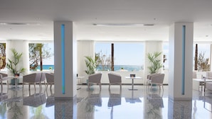 A spacious lobby with a polished floor, seating areas, and large windows offering a view of the sea. - Hotel HSM Golden Playa (Palma de Mallorca)