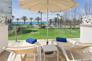 A balcony with a view of a golf course, a table, two chairs, and an umbrella. - Hotel HSM Golden Playa (Palma de Mallorca)