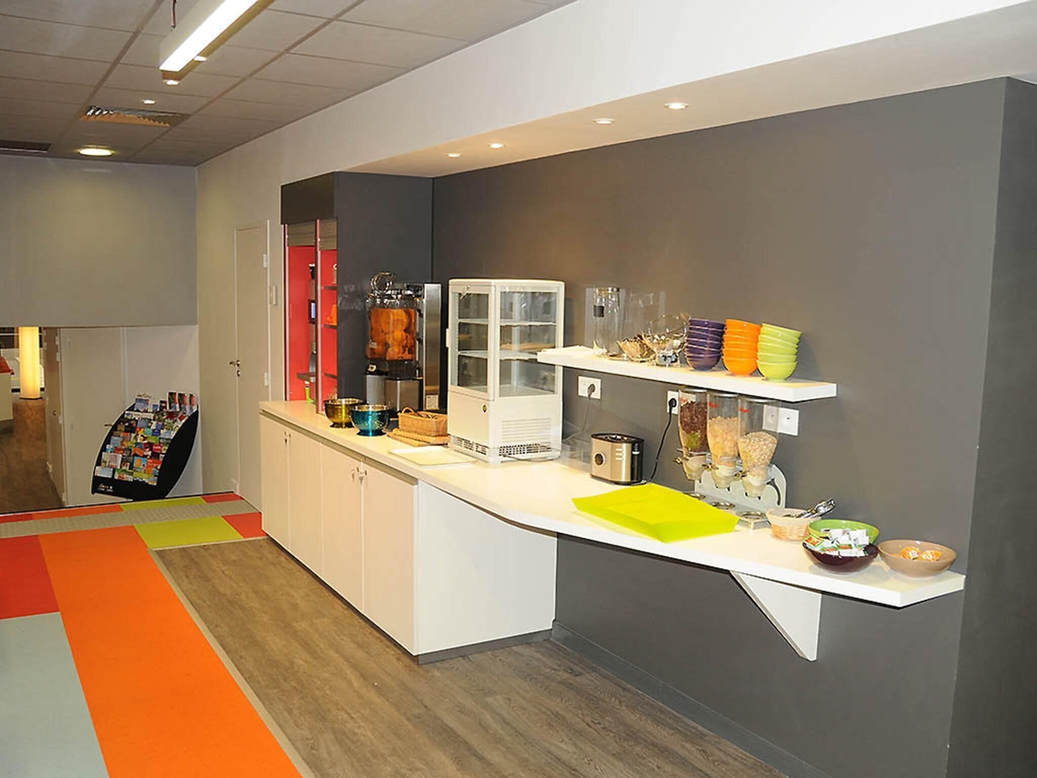 A modern kitchen area with a white countertop, a coffee machine, and various kitchen utensils.