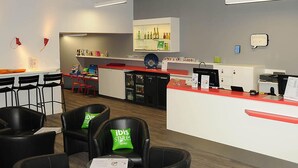 A hotel reception area with a counter, chairs, a bar area, and a display of hotel amenities.