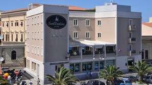 A building with a sign for Hotel Excelsior, featuring a modern facade with balconies and a ground-level entrance. - Hotel Excelsior (La Maddalena)