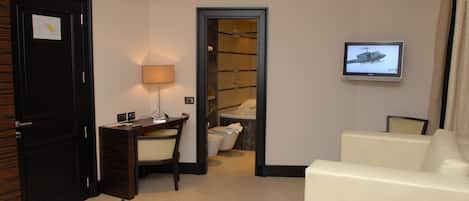 Una camera d'albergo con scrivania, sedia, televisione e zona doccia.