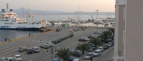 A view of a harbor with parked cars, a ferry, and boats.