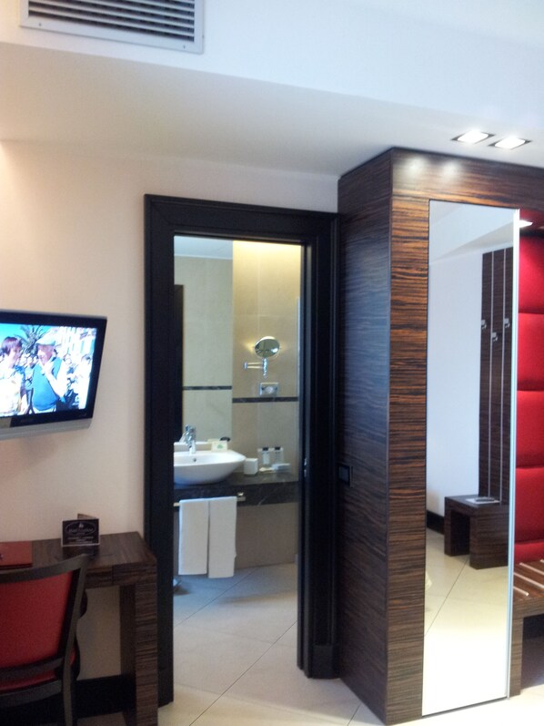 Un baño moderno con un espejo grande, lavamanos y una zona de estar en rojo.