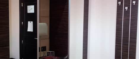A hotel room with a mirrored wardrobe, a small seating area, and a tiled floor.