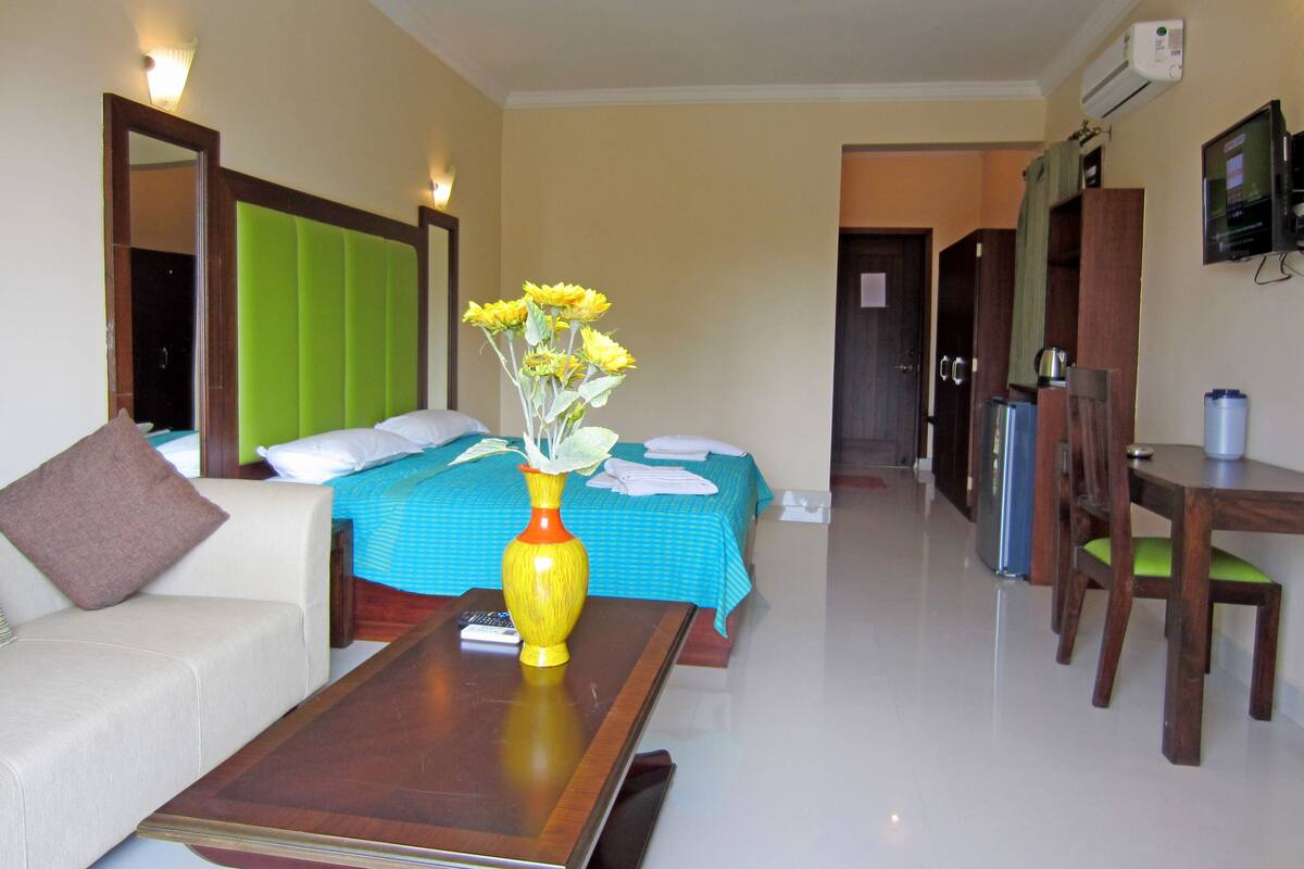 A hotel room with a bed, a sofa, a coffee table, and a desk.
