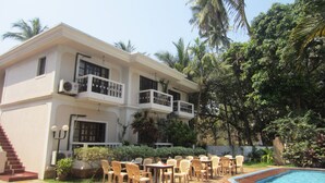 A two-story building with a pool, outdoor seating, and palm trees. - Riverside Regency Resort (Baga)