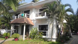 A two-story house with a balcony, surrounded by lush greenery and palm trees. - Riverside Regency Resort (Baga)
