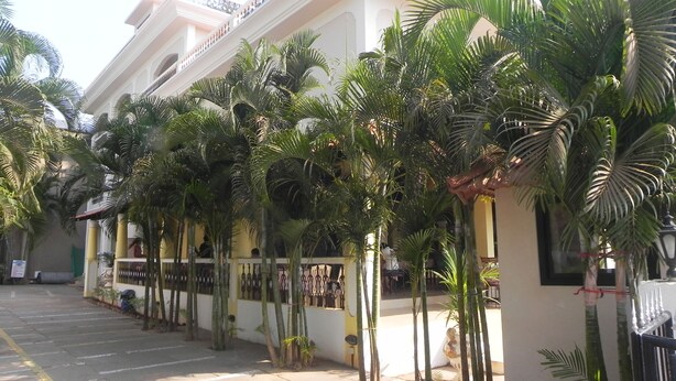 A hotel corridor with palm trees, a tiled floor, and a staircase leading to an upper level. - Riverside Regency Resort (Baga)
