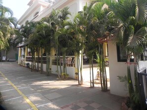 A hotel corridor with palm trees, a tiled floor, and a staircase leading to an upper level. - Riverside Regency Resort (Baga)