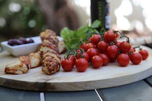 A wooden cutting board with grilled chicken, cherry tomatoes, and a small bowl of olives. - DysART Boutique Hotel (Cape Town)