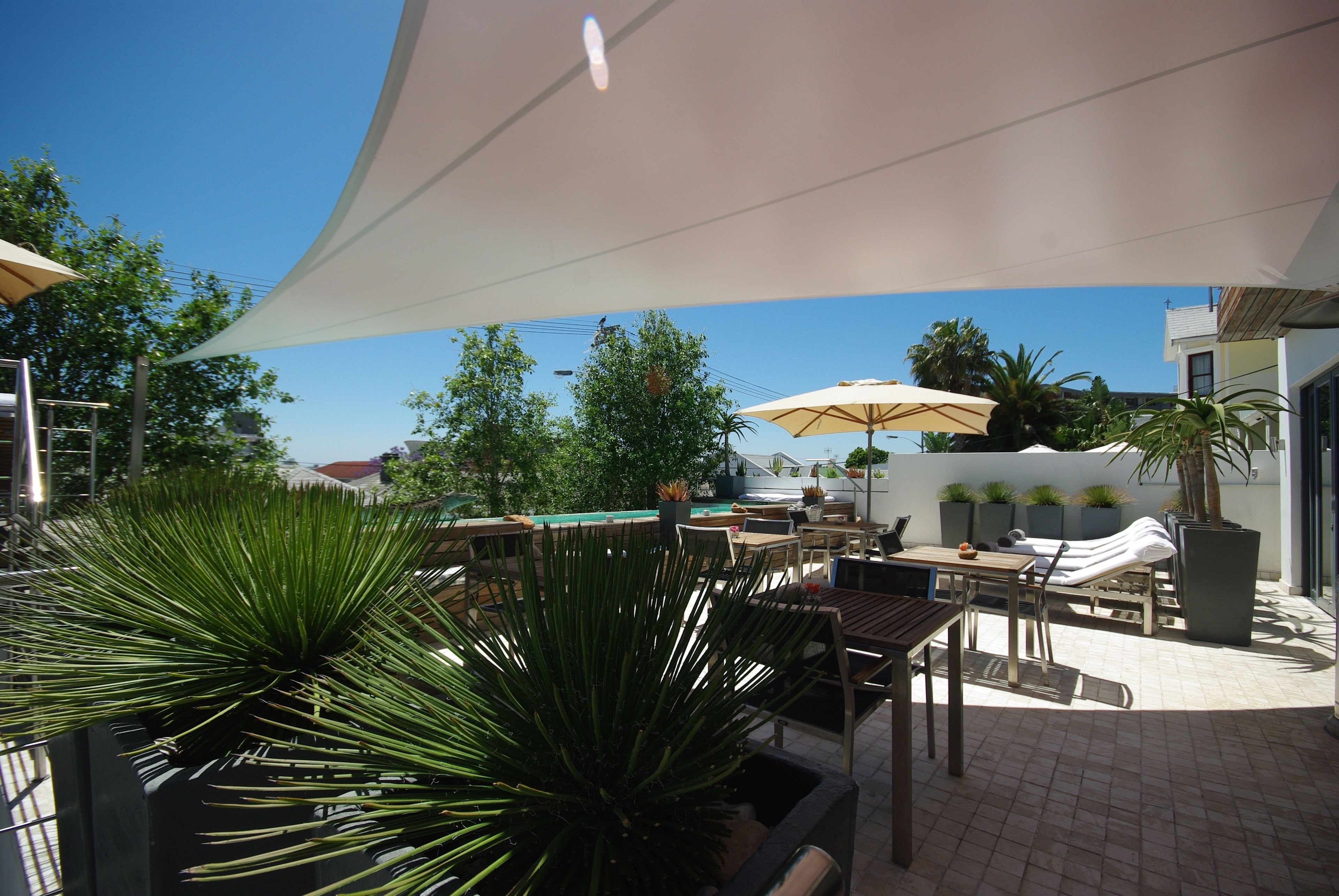 An outdoor patio area with sunshades, seating, and potted plants.