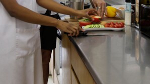 Duas pessoas em uma cozinha preparando comida.