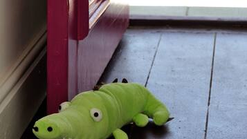 A green plush toy on a wooden floor near a red door.