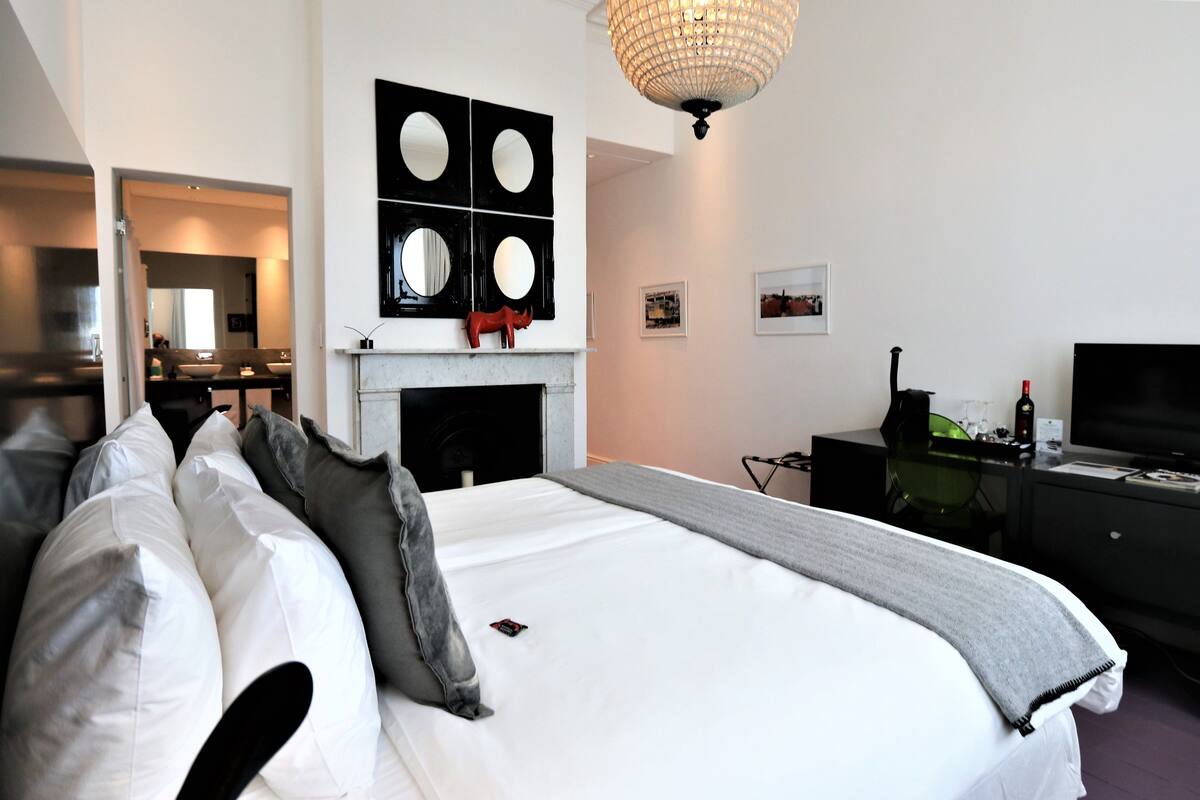 A hotel room with a large bed, a fireplace, a television, and a desk with a computer.