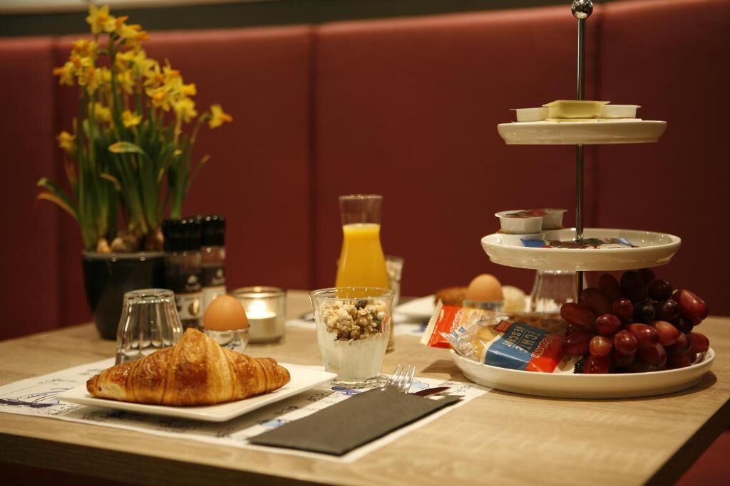 Un desayuno con un croissant, fruta, yogur y un pastel de varios niveles.