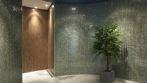 Een modern interieur met een gebogen vloer, een houten deur en een muur bedekt met mozaïektegels.