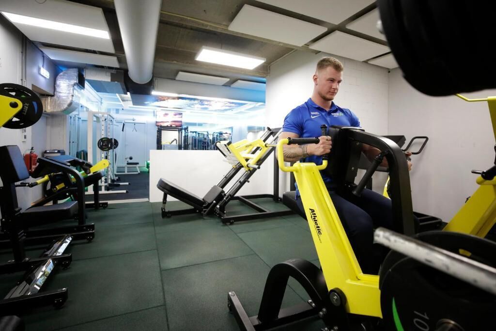 Un gimnasio con diferentes equipos de ejercicio, incluyendo una bicicleta estática amarilla y máquinas de levantamiento de pesas.