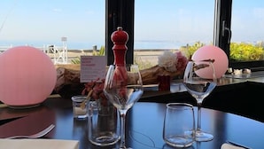 A table set for two with a view of the sea through large windows. - Le Regent & Spa (Pornichet)