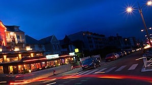A building with multiple stories, a prominent red-lit upper section, and a ground-level commercial area with visible storefronts. - Le Regent & Spa (Pornichet)
