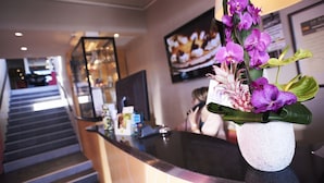 A reception area with a reception desk, a staircase, and a framed picture on the wall. - Le Regent & Spa (Pornichet)