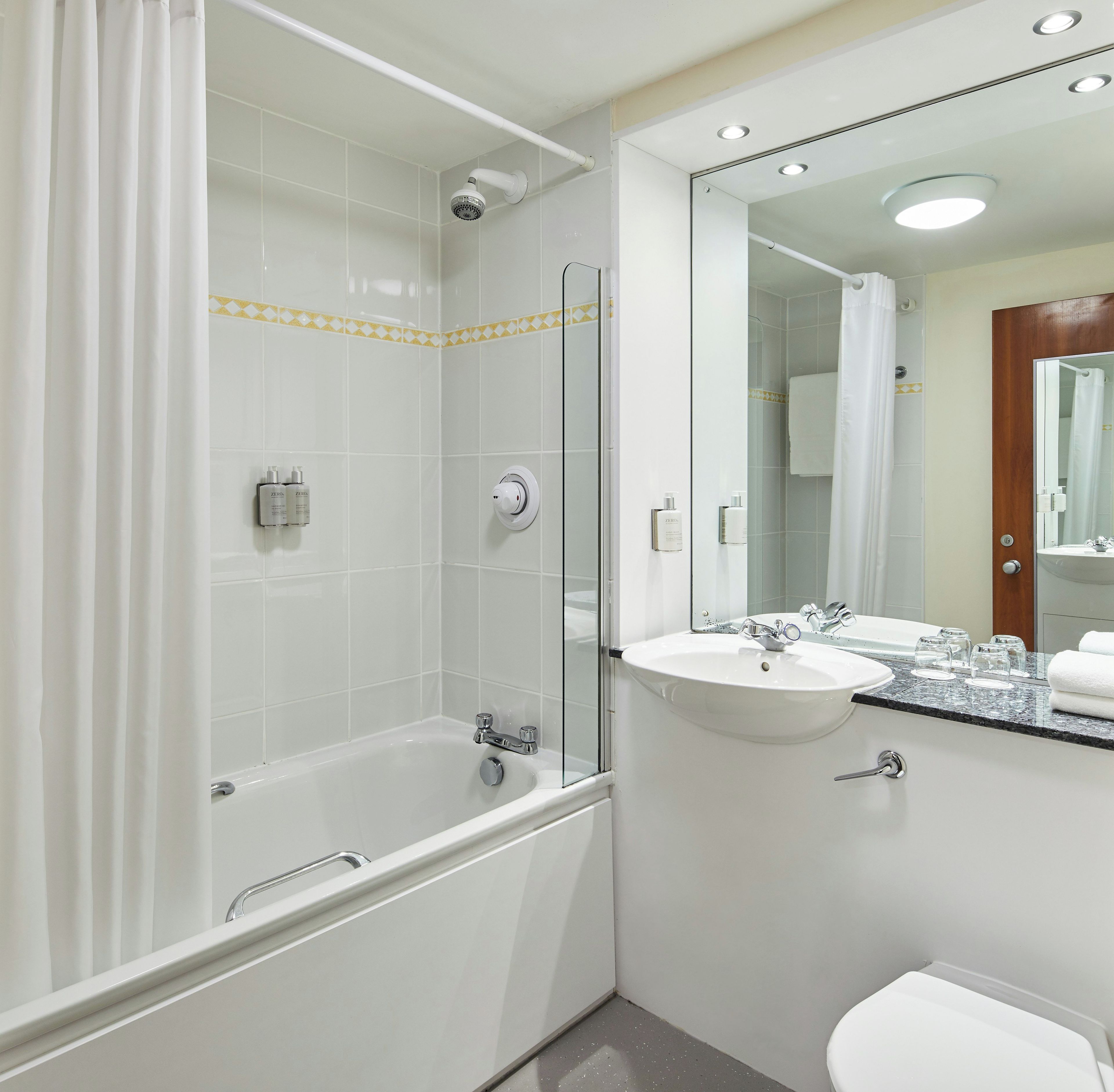 A modern bathroom with a bathtub, a shower, a sink, and a toilet.