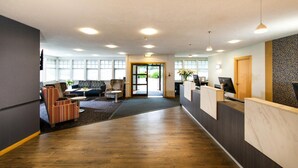 Ein Empfangsbereich mit Holzboden, einer Rezeption, einer Couch und einer Wand mit Muster.