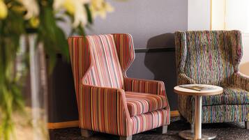 Two striped armchairs and a small round table in a room with a dark carpet and a gray wall.