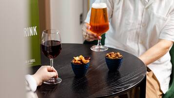 Una persona sosteniendo una jarra de cerveza en una mesa con dos recipientes de aperitivos.