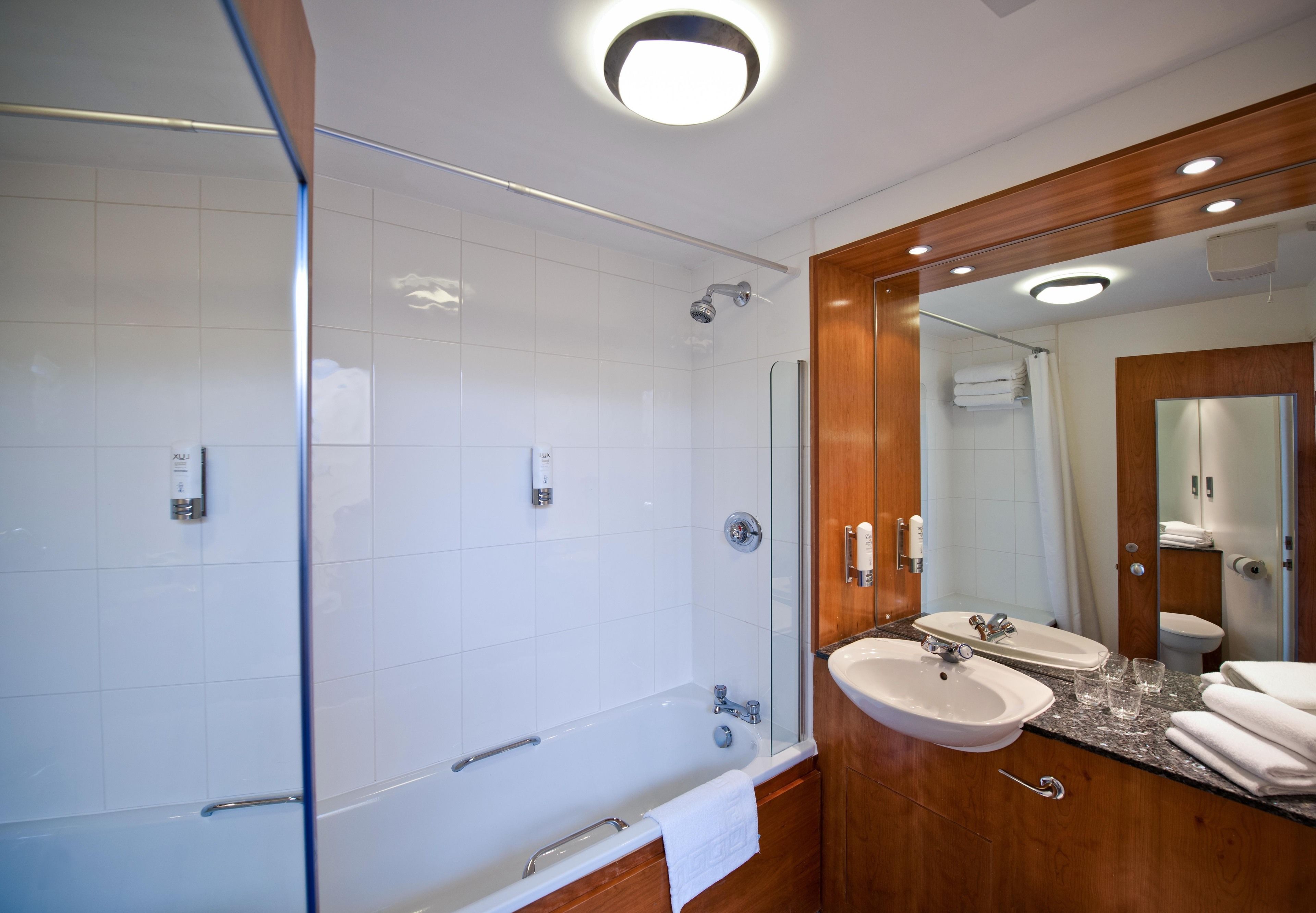 Un bagno moderno con doccia vetro, vasca freestanding e mobile lavabo con lavandino e specchio.