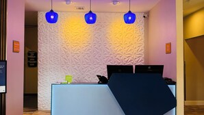 Un comptoir d’accueil avec un mur orné d’un motif géométrique, trois suspensions et un panneau indiquant : « Respirez facilement ».