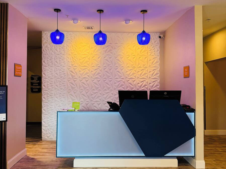 A reception desk with a geometric patterned wall, three pendant lights, and a sign that reads 'Breathe Easy.'