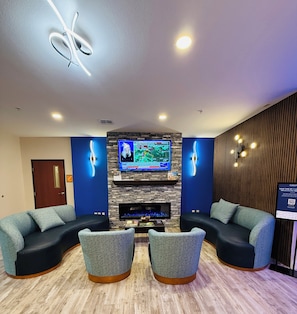 A modern lounge area with a flat-screen TV mounted above a fireplace, two sofas, and a coffee table.