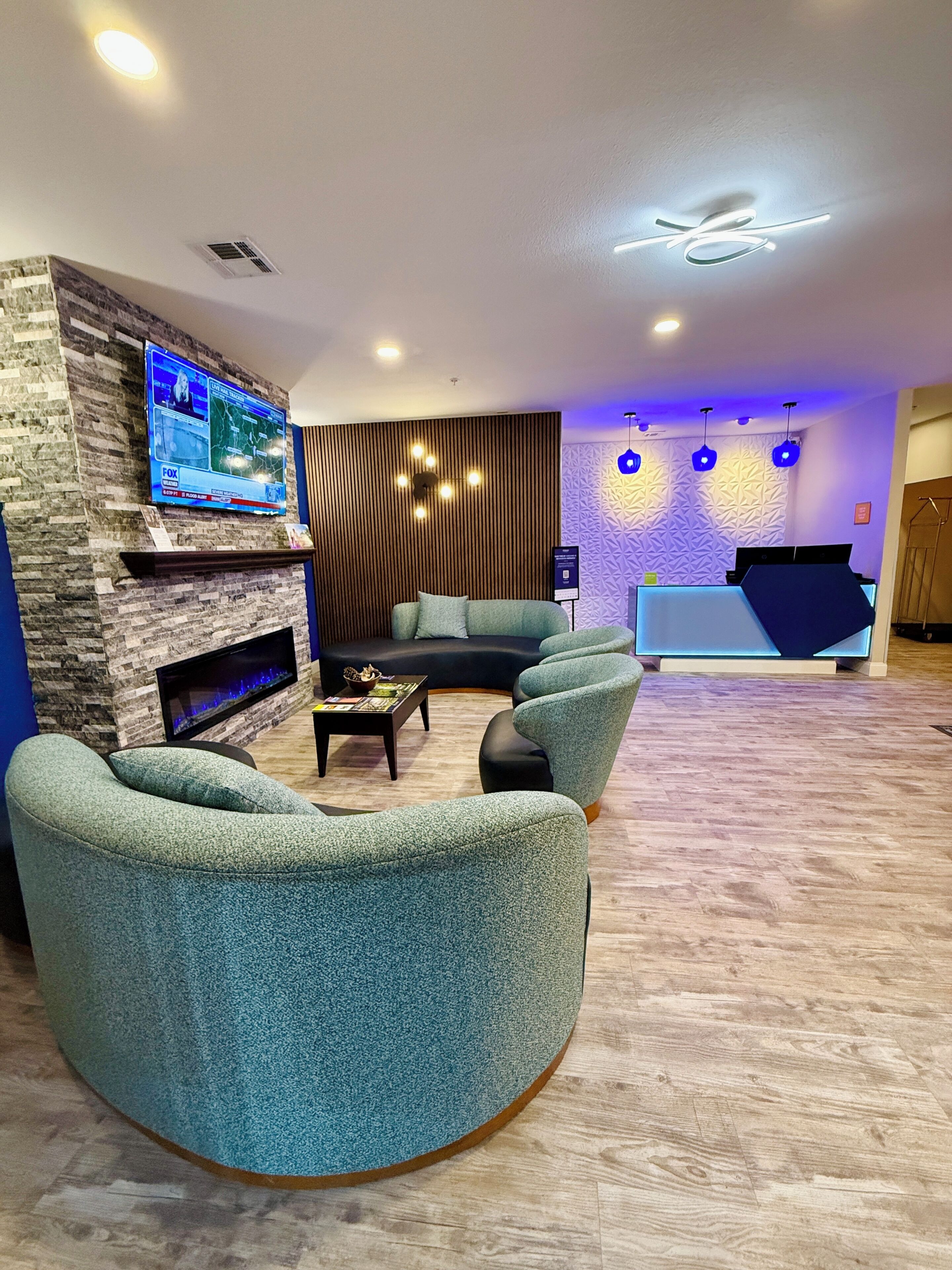 Una sala moderna con chimenea, televisor de pantalla plana y un área de estar con sofás y sillones.