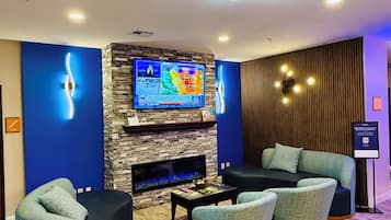 Un salon moderne doté d’un téléviseur à écran plat, d’une cheminée et de sièges confortables.