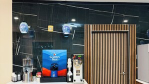 Un espace cuisine moderne comprenant un coin café, un distributeur d’eau et un meuble en bois.