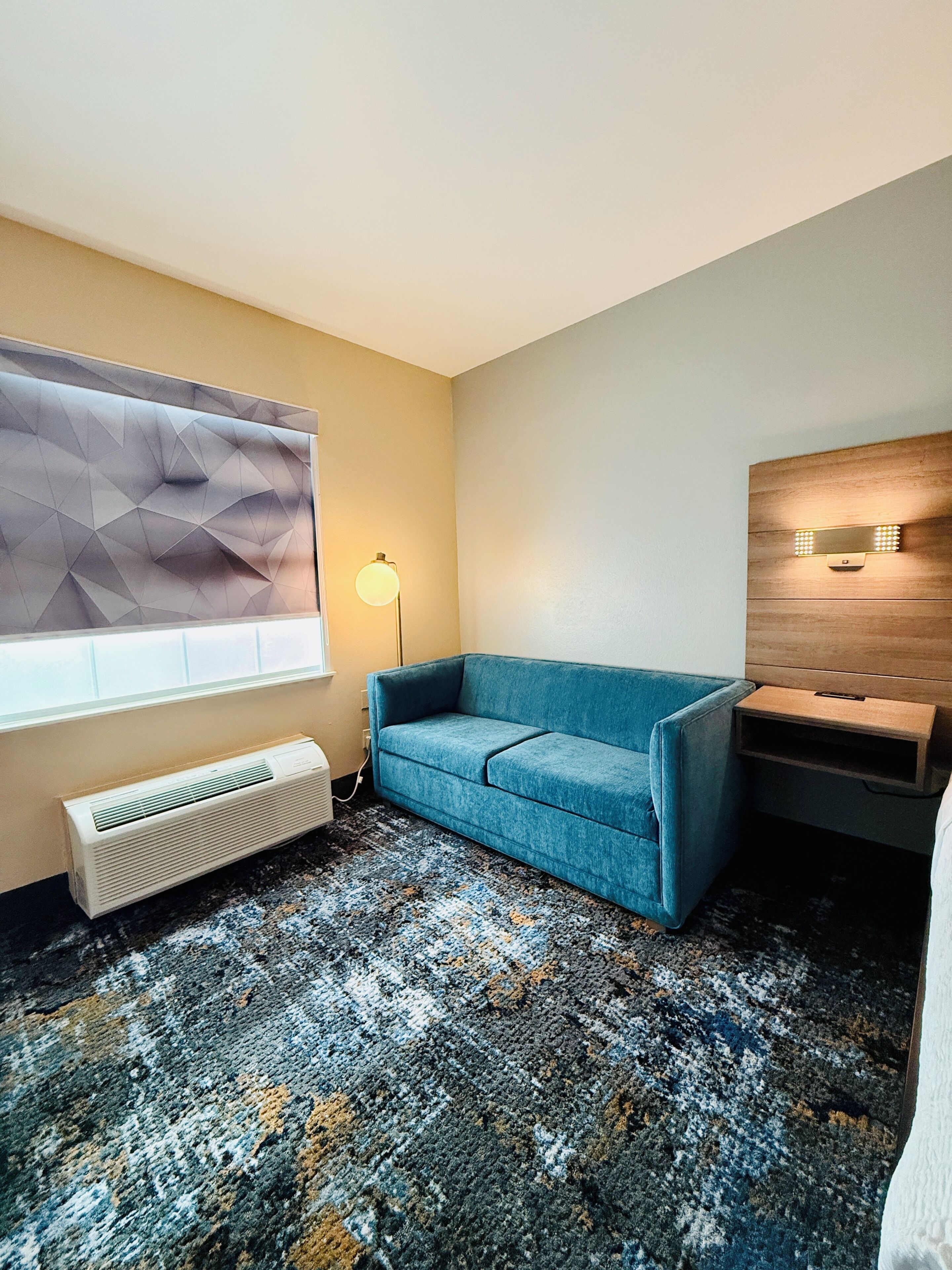 A room with a blue sofa, a radiator, a lamp, and a wall-mounted light fixture.