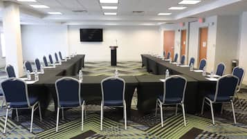 A conference room with a long table, chairs, a podium, and a flat-screen TV on the wall.