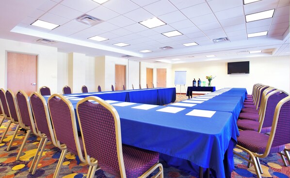 A conference room with a long table, chairs, a projector screen, and a whiteboard.