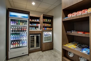 Un espace de libre-service où l’on peut se servir des boissons et des en-cas, avec des distributeurs de boissons réfrigérés, des étagères remplies d’en-cas et un congélateur.