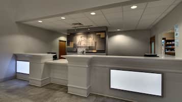 A reception area with a modern design, featuring a reception desk, a digital display, and a wall-mounted sign.