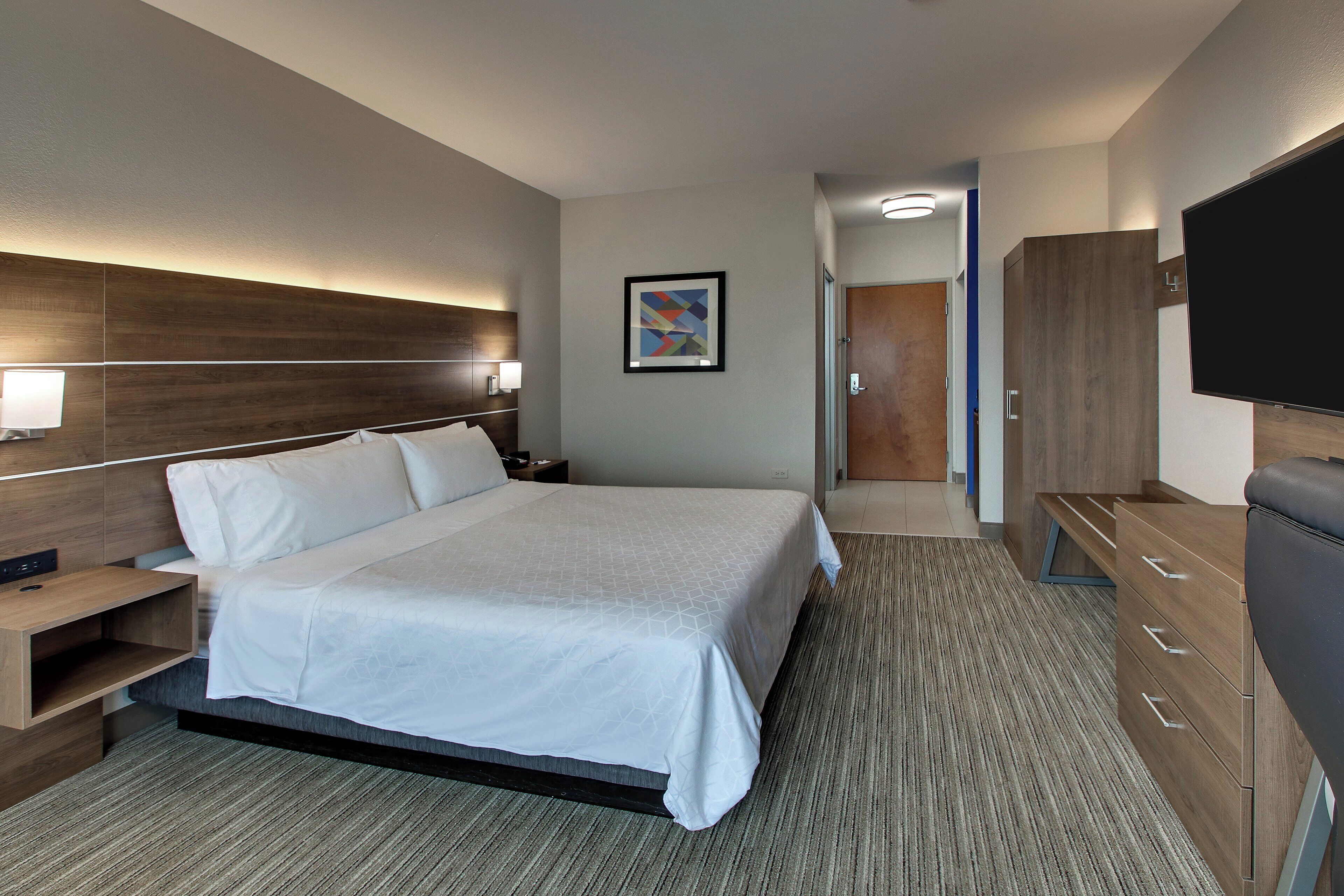 A hotel room with a large bed, a TV, a desk, and a wardrobe.
