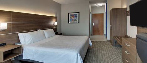 A hotel room with a large bed, a TV, a desk, and a wardrobe.