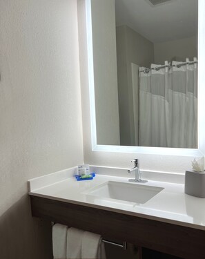 A bathroom with a white sink, a mirror, and a shower curtain. - Holiday Inn Express & Suites Waukegan by IHG (Waukegan)