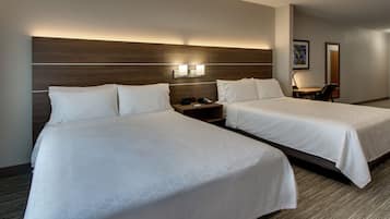 A hotel room with two beds, a desk, and a chair.
