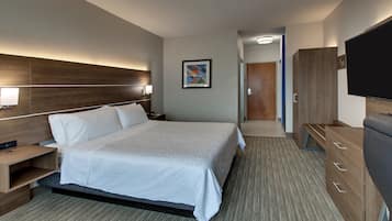 A modern hotel room with a large bed, bedside tables, a flat-screen TV, and a wooden wardrobe.