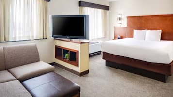 Una habitación de hotel con una cama, un sofá, un televisor y una mesita.