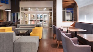 Een moderne lobby met zitgedeeltes, een receptiebalie en een accentmuur van steen.