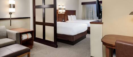A hotel room with a large bed, a desk, a chair, a sofa, and a TV.
