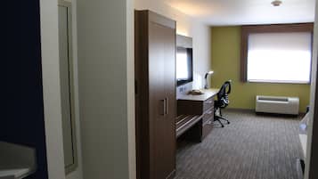 Una habitación de hotel con escritorio, silla y un ventanal grande.